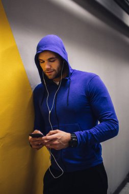 Egzersiz yaparken cep telefonuyla bir yakışıklı sporcu erkek portresi.