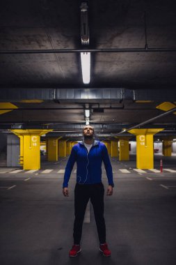 Yakışıklı sporcu bir yer altı otoparkı üzerinde duran.