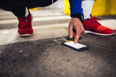 Egzersiz yaparken cep telefonu kullanan bir atlet adam portresi.
