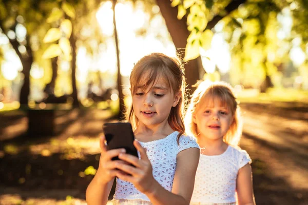 Portrait Two Sister Looking Mobile Phone Park Sunrise — Stock Photo, Image