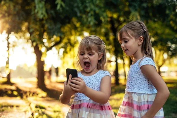 Cute Young Sisters Using Mobile Phone Together — Stock Photo, Image
