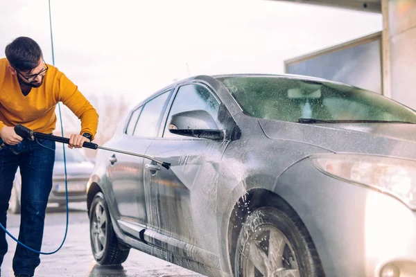 屋外の水で彼の車を洗うハンサムな男性のショット — ストック写真