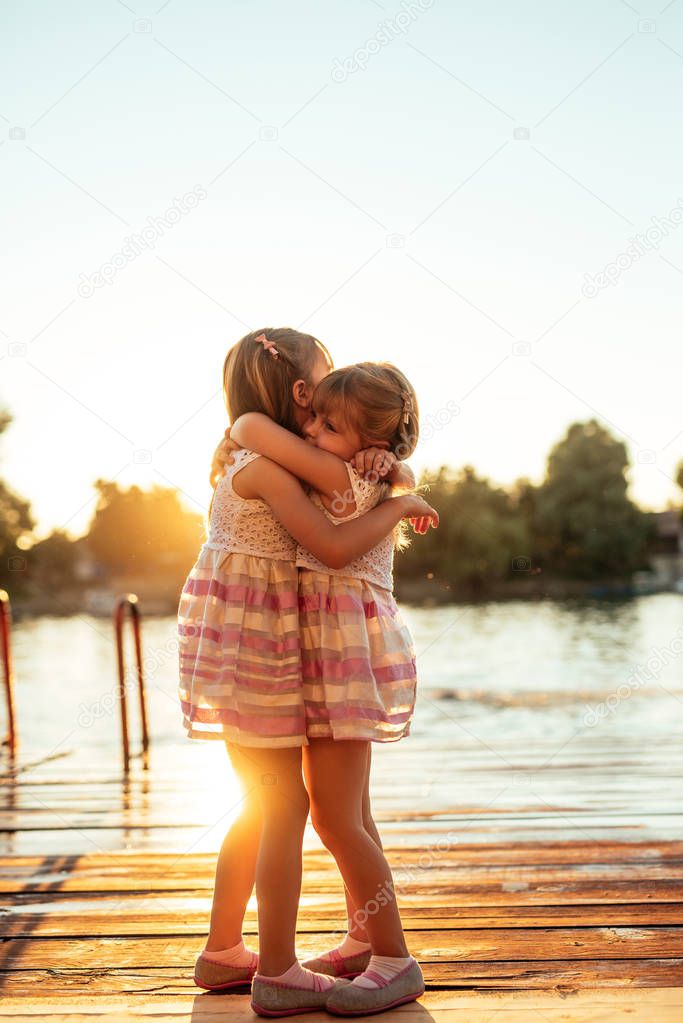 Rear view of two young sisters hugging each other.