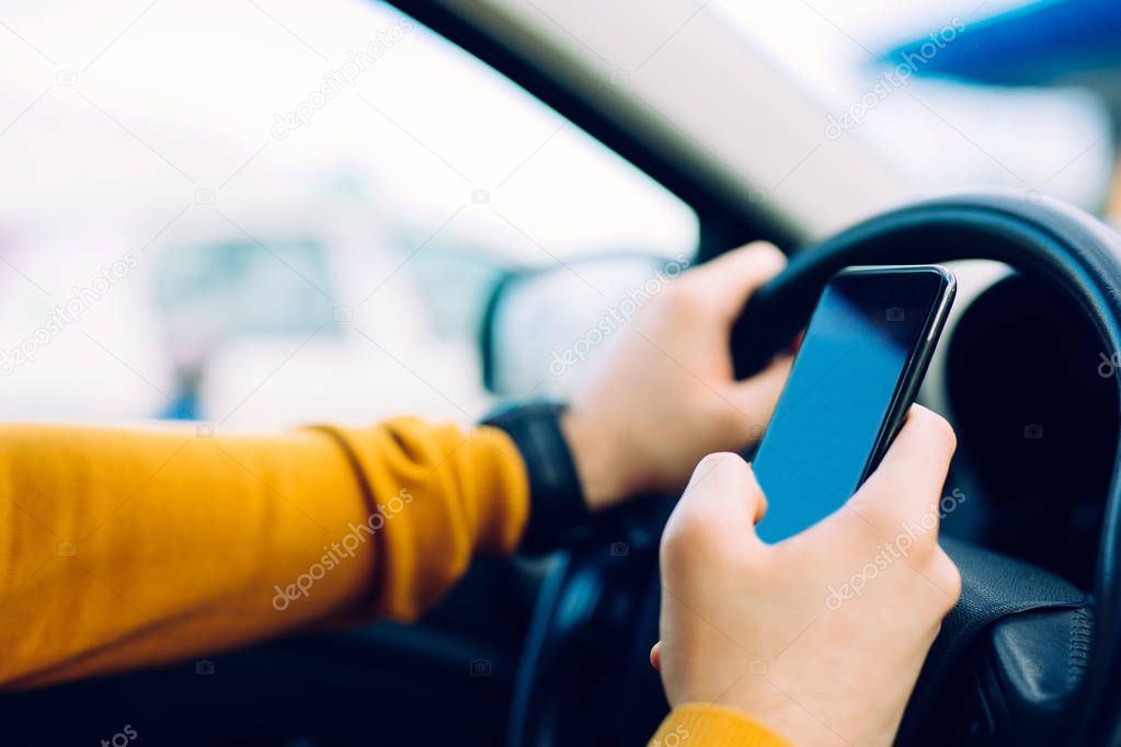 Close up photo of a man using mobile phone while driving.