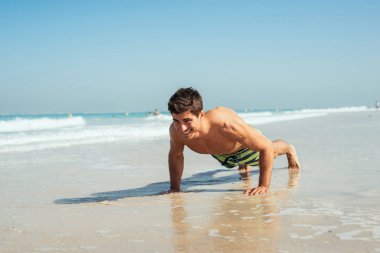 Bazı yapan yakışıklı erkek push up sahilde.