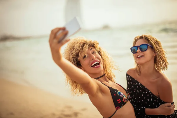 身穿泳装 开心的金发女孩微笑的画像在海滩上用手机拍照 — 图库照片