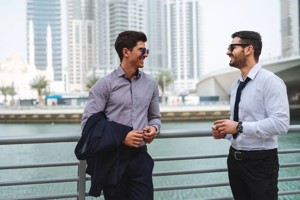 Two businessmen having an outdoor meeting while walking by the river.