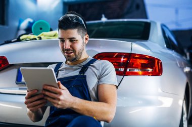 Bir Tablet bir atölyede çalışan genç automechanical.