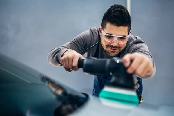 Man doing a car polish with a machine.