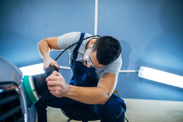 Man doing a car polish with a machine.