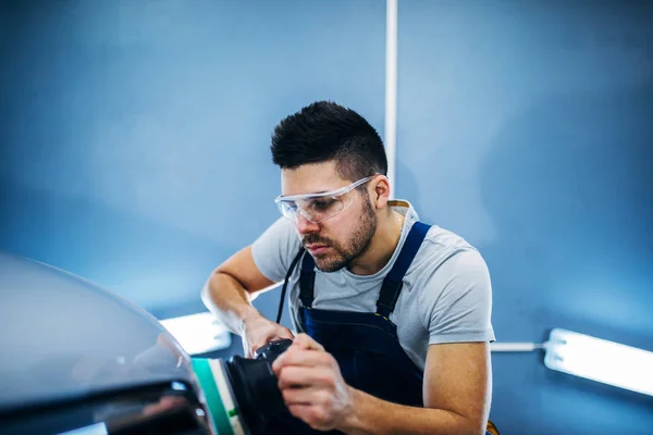 Man doing a car polish with a machine.