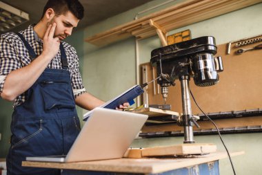 Genç marangoz atölyesinde ölçme portresi.