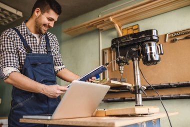 Mutlu bir genç marangoz atölyesinde bir dizüstü bilgisayar üzerinde çalışan zevk şans.