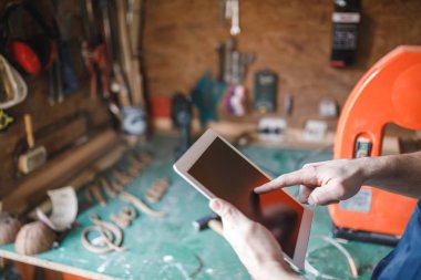 Fotoğraf dijital tablet iş üstünde tutan bir marangoz.