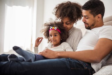 Afro-Amerikan aile yatağın üstüne oturan birbirleri ile yapıştırma.