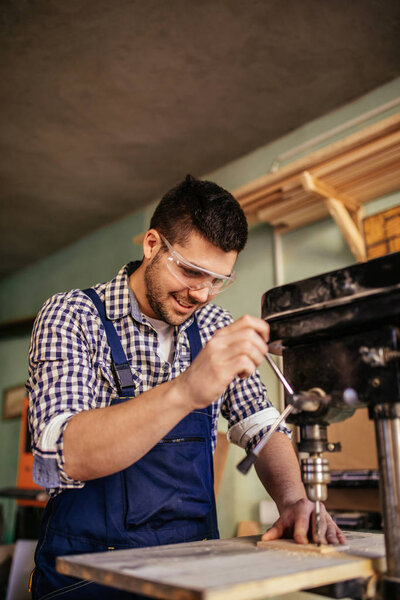 Young carpenter working on a machine in his workshop.