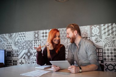 Dijital tablet kullanma ve evden çalışan genç çift portresi.