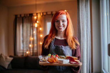 Happy ginger girl bringing food for dinner. clipart