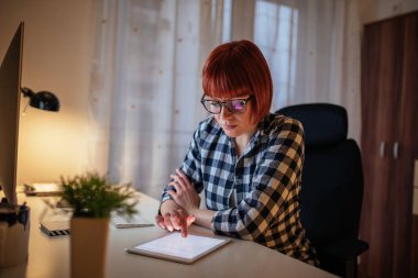 Dijital tablet üzerinde çalışan genç bir kadın fotoğrafı.
