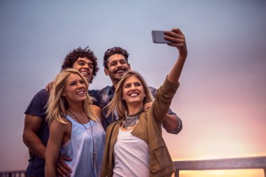 Gün batımında köprüde şehir selfies alarak arkadaşlar.