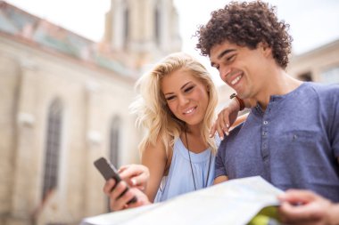 Mutlu genç turist konumu hem cep telefonu ve harita üzerinde arama. 