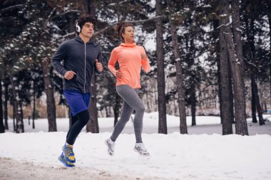 Ormanda bir kış gününde çalışan iki atletik kişi fotoğrafı.