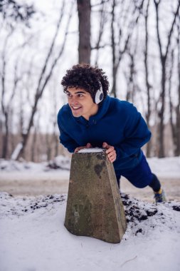 Müzik dinlerken onun sabah egzersiz rutin ormanda üzerinde uzanan bir genç atlet portresi.