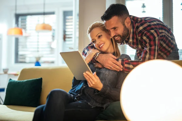 微笑的年轻夫妇 粘接和在家里玩数字平板电脑的照片 — 图库照片