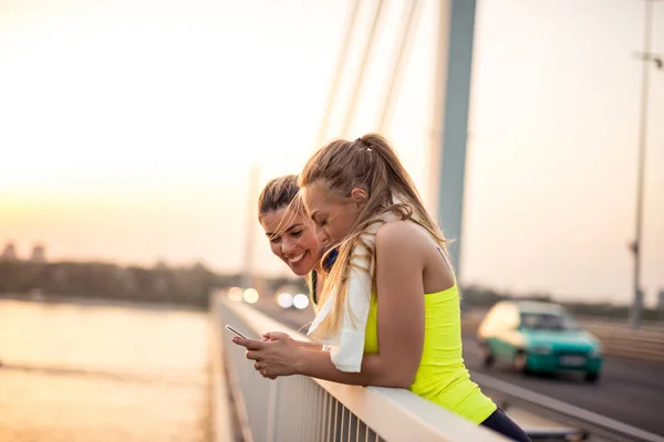 Две Спортивные Девушки Пользуются Мобильным Телефоном Открытом Воздухе — стоковое фото