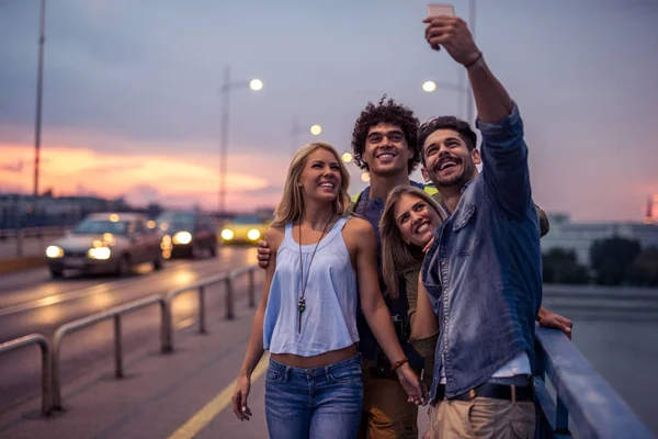 Φίλοι Για Λήψη Selfie Της Πόλης Στη Γέφυρα Κατά Ηλιοβασίλεμα — Φωτογραφία Αρχείου