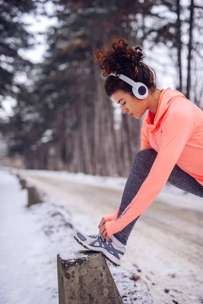 Молодая Спортсменка Завязывает Шнурки Пне Слушает Музыку Время Зимней Тренировки — стоковое фото