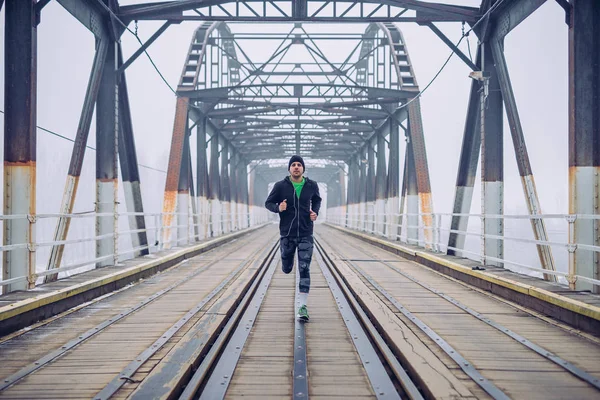 Photo of a male running on the train bridge and listening to music.