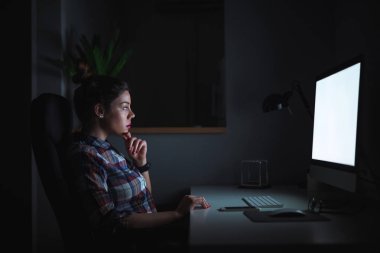 Gece geç saatlerde çalışan bir genç iş kadını portresi. O masada oturuyor ve bilgisayar arıyorum.