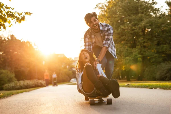 享受在日落时分在街上玩滑板一笑对年轻夫妇的肖像 — 图库照片