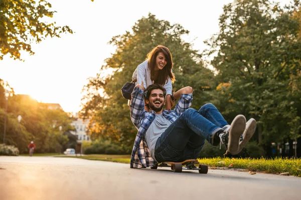 微笑着对幸福的夫妻玩滑板在户外的镜头 — 图库照片