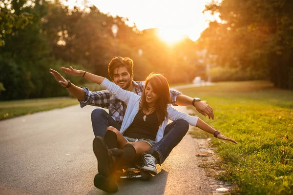 关闭了对幸福的夫妻享受日落时分在街上玩滑板的肖像 — 图库照片