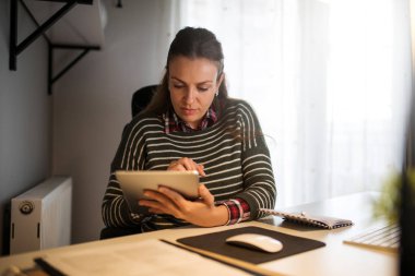 Dijital tablet kullanarak evden çalışan meşgul kadın.