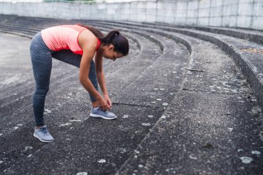 Genç spotswoman açık çalıştırırken bir bağcık bağlama.