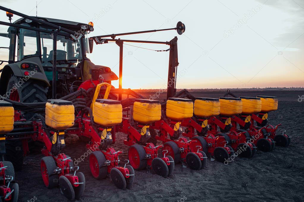 Tractor working on farm land on sunset.