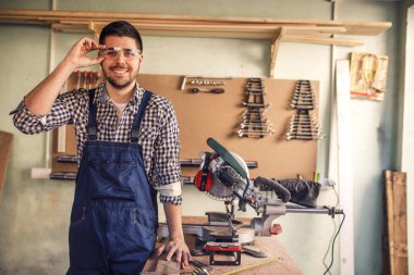 Genç yakışıklı marangoz gülümseyerek portresi atölye tabloda eğildi.