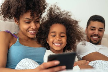 Afro-Amerikan aile yatakta tablet kullanma.