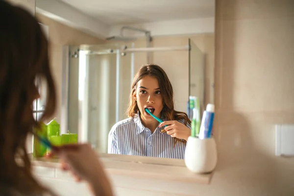 Retrato Uma Bela Mulher Escovando Dentes Olhando Espelho Banheiro — Fotografia de Stock