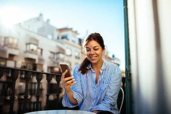 美丽的女人发短信对坐在阳台上电话 — 图库照片