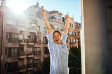 Güzel kadın kollarını sabah bir balkonda germe..