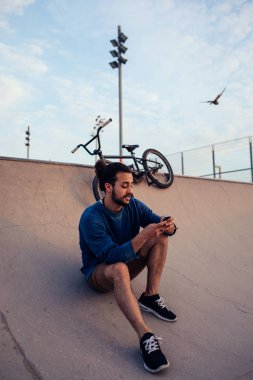 Bir mola verme ve telefonunu kontrol genç Bmx sürücüsü.