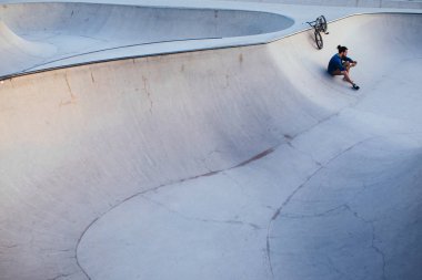 Bir mola verme ve telefonunu kontrol genç Bmx sürücüsü.