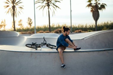 Ayakkabısını bağlıyor ve Bisiklete binmek için hazır Başlarken yakışıklı motorcu.