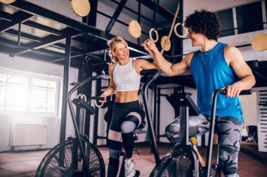 Genç çift birlikte bir saldırı hava Bisiklet spor salonunda egzersiz gülümseyen fotoğraf.