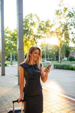 Bir bavul kablolarıylaberaber cep telefonuyla bir başarılı bir iş kadını portresi.