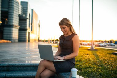 Dizüstü bilgisayar açık havada günbatımında kullanarak bir genç iş kadını vurdu.